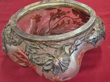 un vase en argent contenant un verre, posé sur un tissu rouge