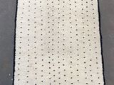 a white rug with black dots and fringes on it