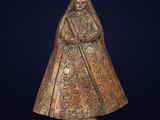 une statue antique en bronze représentant une femme vêtue d'un manteau et d'un chapeau