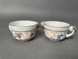 two cups with floral designs on them sitting on a table