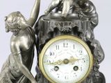 a silver clock with a statue on top of it