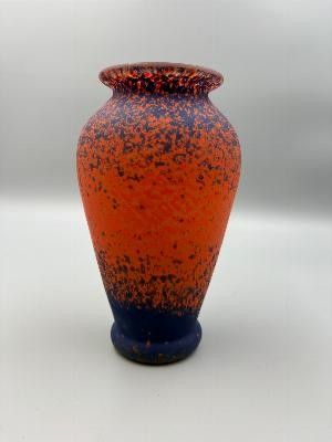 a red and blue vase sitting on a white surface