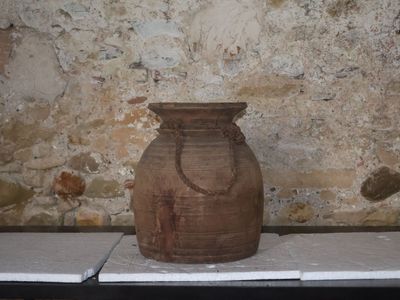 un vase marron posé sur une table devant un mur de pierre