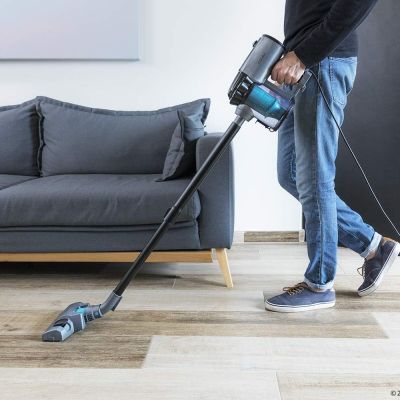 man using a corded vacuum to clean a living room floor