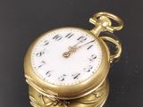une montre de poche en or posée sur une surface noire avec un fond noir