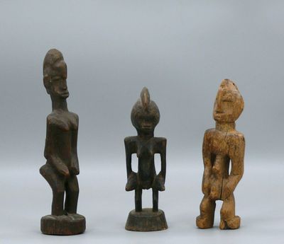 three wooden figurines of different shapes and sizes on a white surface