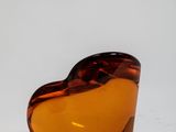 an orange glass heart shaped object sitting on top of a white surface
