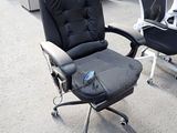 a black office chair with a remote control in the middle of the room