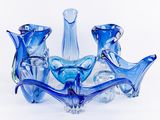 plusieurs vases en verre bleu empilés les uns sur les autres sur une surface blanche