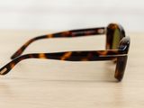 sunglasses on a wooden table with a white wall in the background