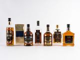 several bottles of different types of whiskey are lined up on a white surface
