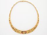 un collier en or orné de pierres multicolores sur fond blanc
