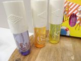 three different bottles of lip balm sitting on a wooden board