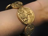 someone is wearing a gold bracelet with a gold coin on it