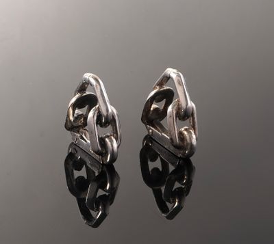 a pair of silver earrings sitting on top of a black surface