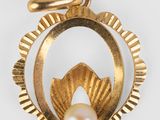 un gros plan d'un pendentif en or serti d'une perle