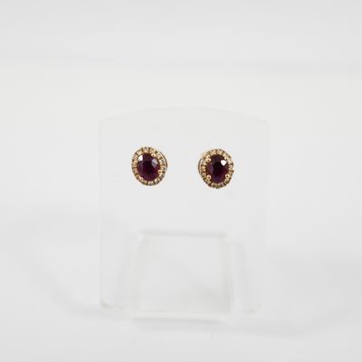 une paire de boucles d'oreilles en rubis et diamants, présentées sur un socle transparent