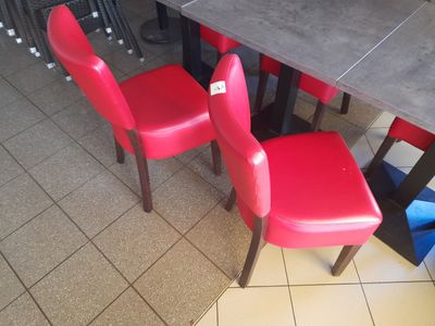 quatre chaises rouges disposées autour d'une table au milieu d'une pièce
