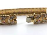 gold bracelet with pink and white stones on a white surface
