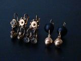three pairs of earrings on a black surface with a blue background