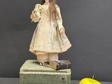 a doll standing on top of a suitcase next to an apple