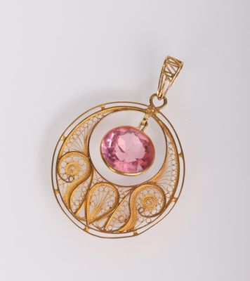 un gros plan sur un pendentif en or orné d'une pierre rose