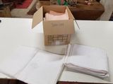 une boîte de serviettes pliées posée sur une table, à côté d'une autre boîte de serviettes pliées
