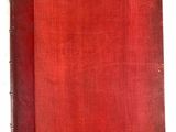 un vieux livre à la couverture rouge posé sur une surface blanche