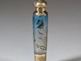 an antique glass perfume bottle with gold trim and a blue flower on it