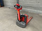 a red and black forklift sitting in front of a garage door