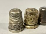 three antique thimbles are sitting on a white surface
