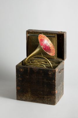 une petite boîte en bois contenant une corne rouge et dorée