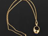 un collier en or avec une pierre bleue suspendue à une chaîne