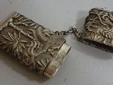 two pieces of silver jewelry are sitting on a white surface
