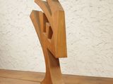 a wooden sculpture sitting on a wooden bench in front of a white wall