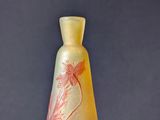 a yellow vase with a red flower on it on a table