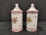 two white and pink ceramic containers with flowers on them