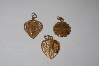 trois breloques dorées sur une surface blanche, sur fond blanc