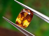 un gros plan d'un diamant jaune tenu par une paire de pinces