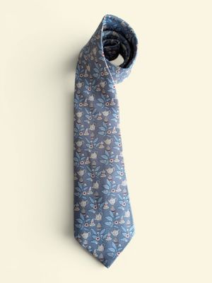 une cravate à motifs floraux bleus et blancs accrochée à un mur blanc