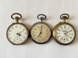 trois montres de poche anciennes posées côte à côte sur une surface blanche