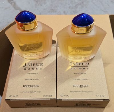 two bottles of perfume sitting on top of a box on a table