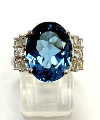 gros plan d'une bague avec une pierre bleue entourée de diamants