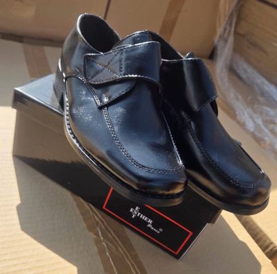 des chaussures en cuir noir posées sur une boîte, avec un bâton en bois