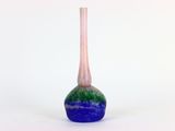 un vase bleu et vert posé sur une surface blanche