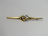 a close up of a gold tie bar with a knot on it