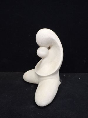 une sculpture blanche représentant une personne assise sur une surface noire