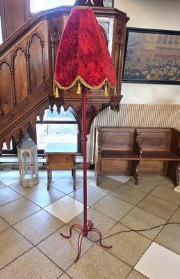 une lampe rouge posée sur un pied dans une pièce