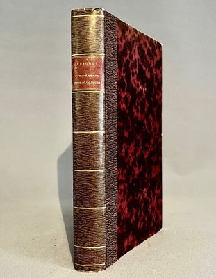 un vieux livre posé sur une table à côté d'un mur blanc