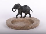 statue d'un éléphant posée sur un socle en pierre, sur fond blanc